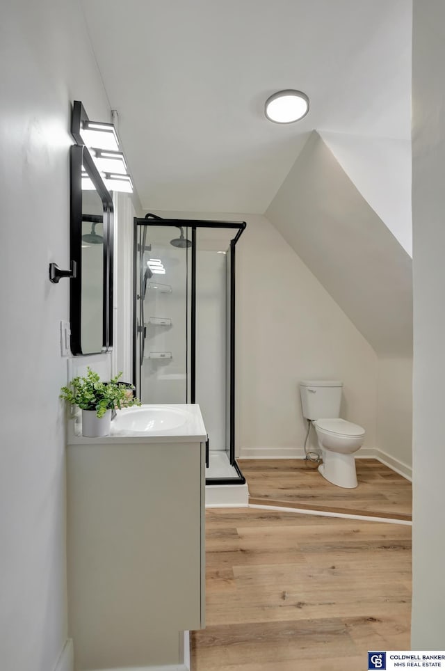 bathroom with vaulted ceiling, hardwood / wood-style flooring, vanity, an enclosed shower, and toilet