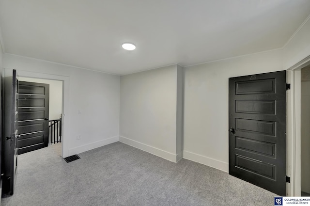 empty room featuring crown molding and light carpet