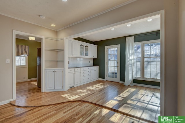 kitchen featuring ornamental molding, a wealth of natural light, light hardwood / wood-style flooring, and white cabinets