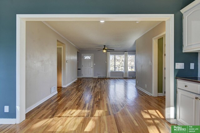 unfurnished living room with ornamental molding, ceiling fan, and light hardwood / wood-style floors