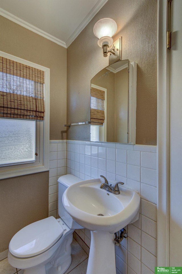 bathroom with tile walls, crown molding, and toilet