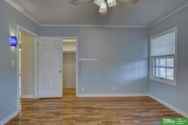 unfurnished bedroom with crown molding, a spacious closet, a closet, ceiling fan, and light hardwood / wood-style floors