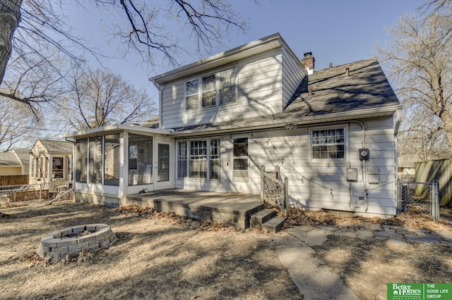 rear view of house with an outdoor fire pit and a sunroom