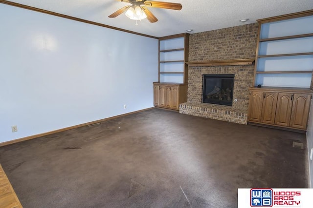 unfurnished living room with ceiling fan, a fireplace, ornamental molding, a textured ceiling, and dark carpet