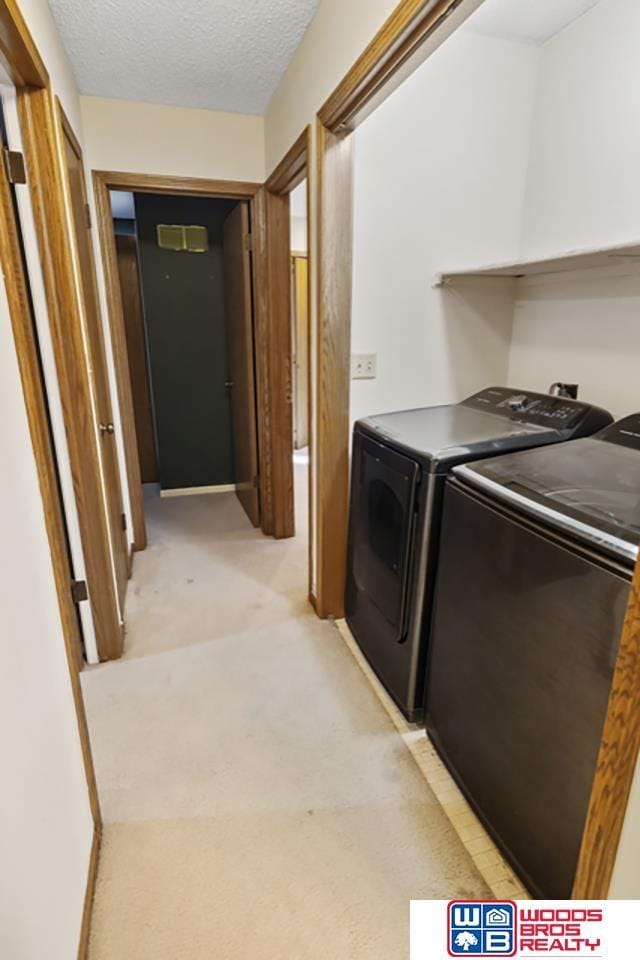 washroom with independent washer and dryer, light colored carpet, and a textured ceiling