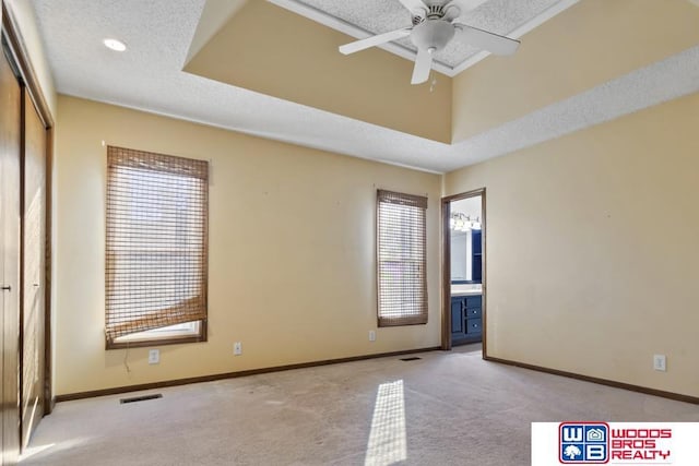 spare room featuring ceiling fan, light colored carpet, a tray ceiling, and a textured ceiling