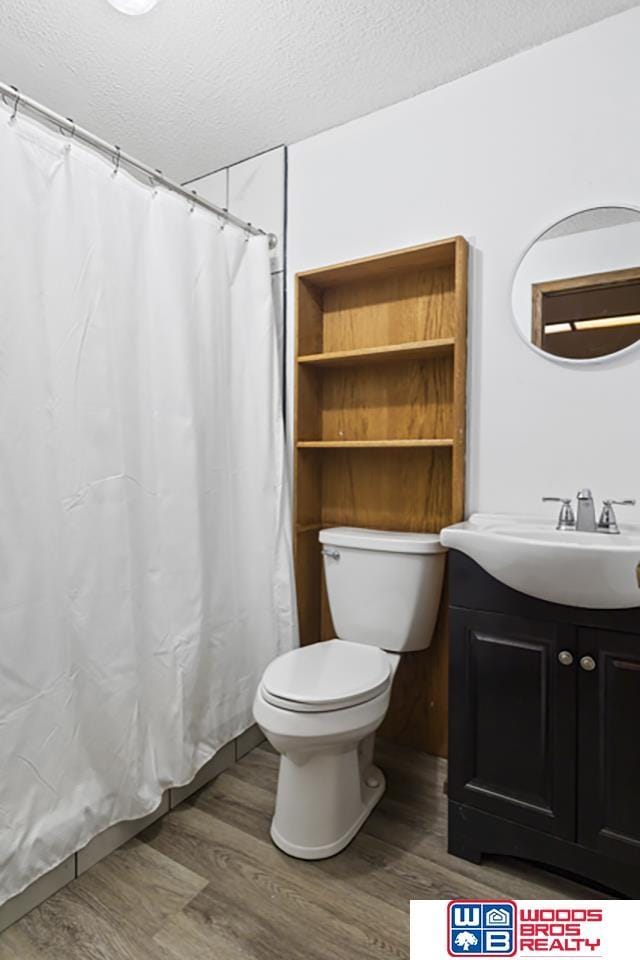 bathroom with hardwood / wood-style flooring, vanity, toilet, and a textured ceiling