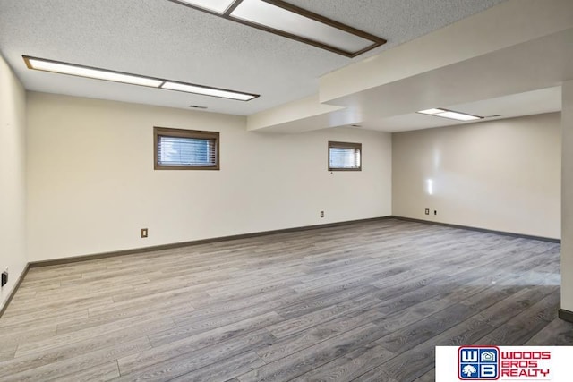 basement featuring a textured ceiling and light hardwood / wood-style floors