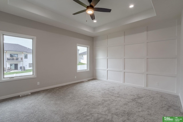 unfurnished room featuring a tray ceiling, ceiling fan, and carpet flooring