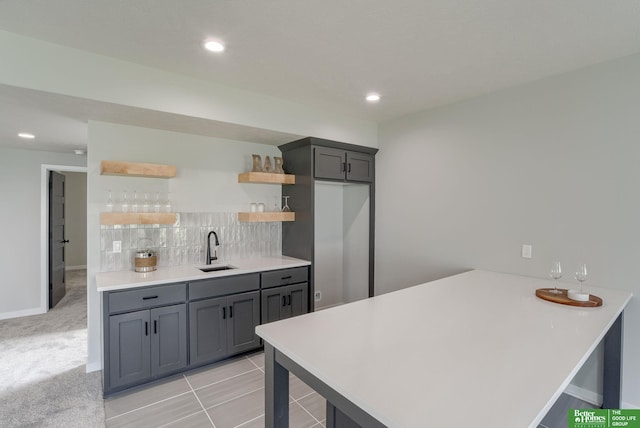 kitchen featuring sink, gray cabinetry, light carpet, decorative backsplash, and kitchen peninsula