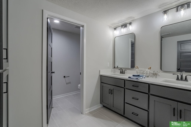 bathroom featuring vanity, a textured ceiling, tile patterned floors, and toilet