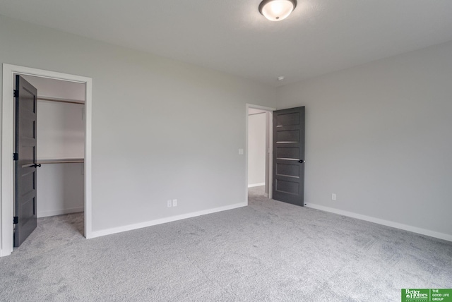 unfurnished bedroom featuring light carpet, a spacious closet, and a closet