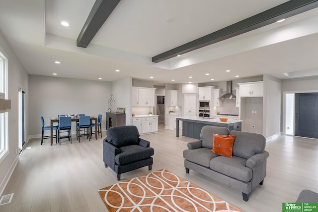 living room with sink, beam ceiling, and light hardwood / wood-style flooring