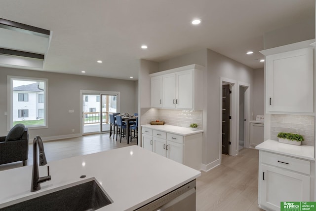 kitchen with dishwasher, white cabinetry, sink, and light wood-type flooring