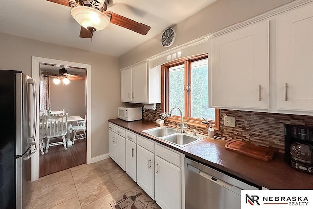 kitchen with appliances with stainless steel finishes, sink, decorative backsplash, and white cabinets