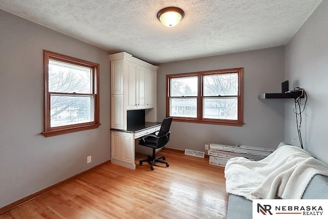 home office featuring light hardwood / wood-style flooring and a textured ceiling