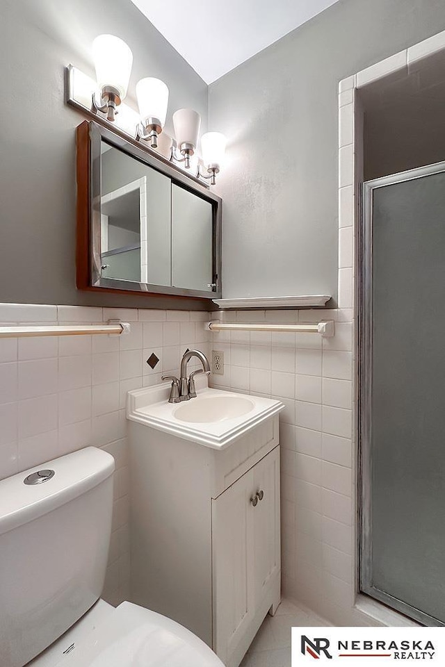 bathroom featuring tile walls, vanity, toilet, and walk in shower