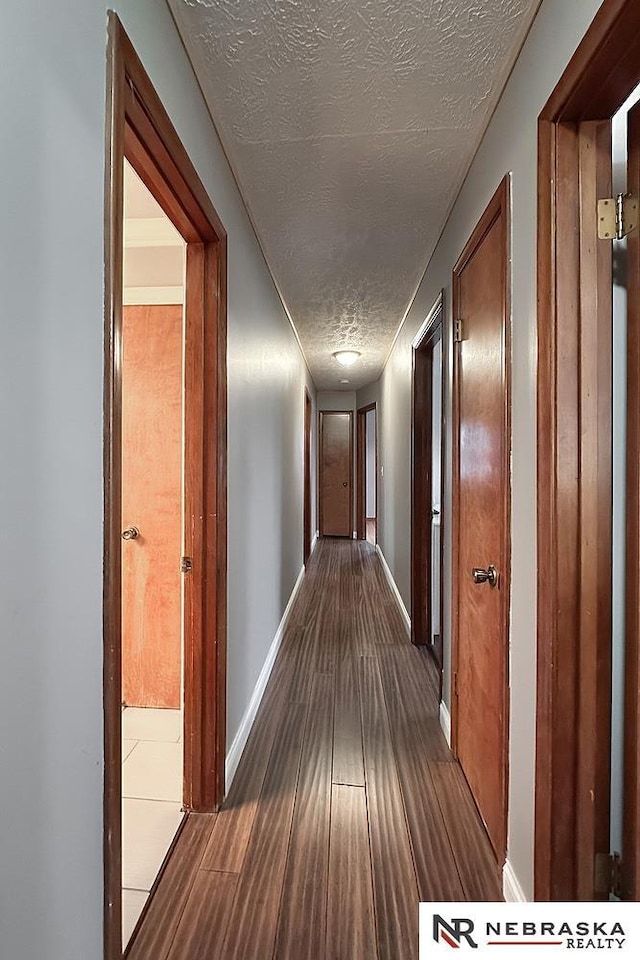 hallway with hardwood / wood-style flooring and a textured ceiling