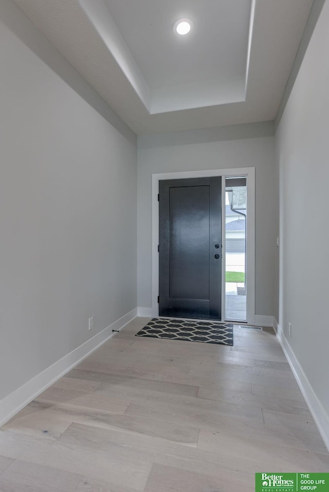 entrance foyer with a raised ceiling and light wood-type flooring