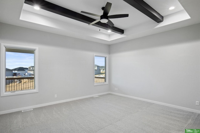 carpeted spare room with beam ceiling, a raised ceiling, and ceiling fan