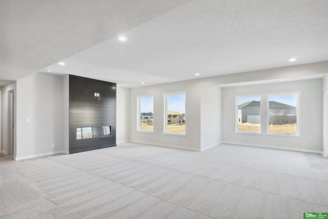 unfurnished living room featuring a large fireplace and light colored carpet