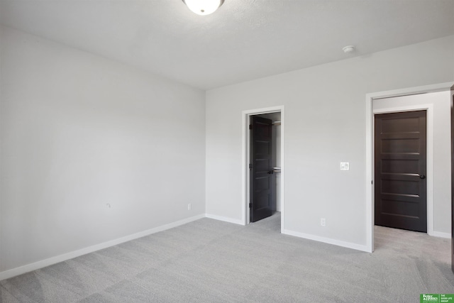 unfurnished bedroom featuring a spacious closet, light colored carpet, and a closet