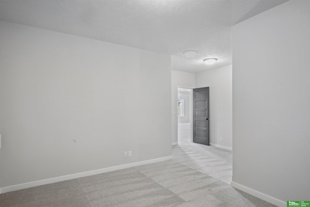 spare room with light carpet and a textured ceiling