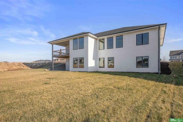 rear view of property featuring a balcony and a yard