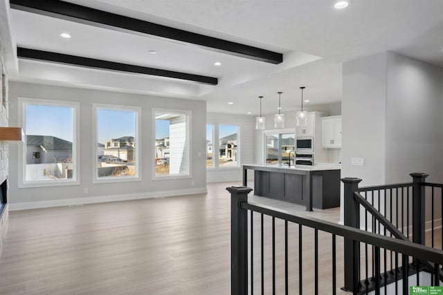 kitchen with pendant lighting, sink, white cabinetry, a center island with sink, and built in microwave