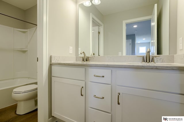 full bathroom featuring hardwood / wood-style flooring, vanity, shower / bath combination, and toilet