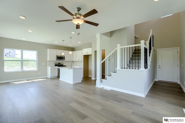 unfurnished living room featuring sink, ceiling fan, and light hardwood / wood-style flooring