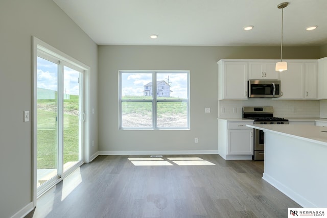 kitchen with stainless steel appliances, decorative backsplash, white cabinets, and decorative light fixtures