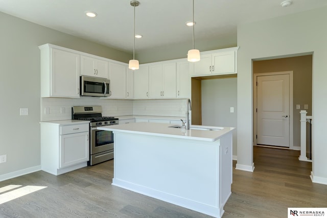 kitchen with pendant lighting, sink, white cabinetry, a kitchen island with sink, and stainless steel appliances