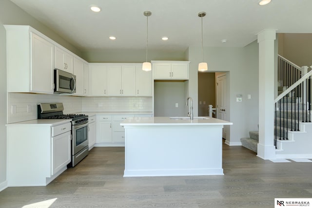 kitchen with sink, white cabinetry, a center island with sink, appliances with stainless steel finishes, and pendant lighting