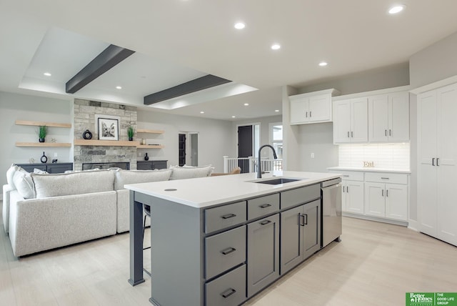 kitchen featuring an island with sink, gray cabinets, sink, and white cabinets