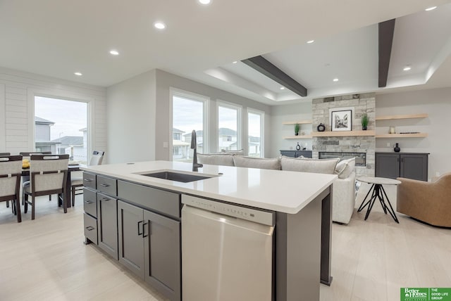 kitchen featuring gray cabinetry, sink, dishwasher, and a center island with sink