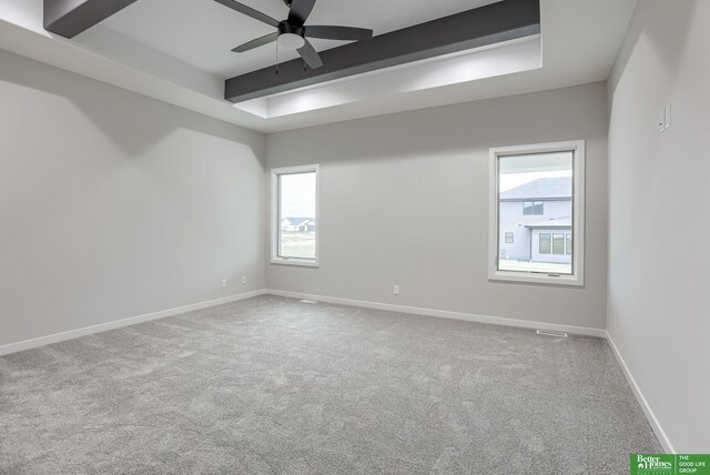 unfurnished room featuring beamed ceiling, carpet, a healthy amount of sunlight, and ceiling fan