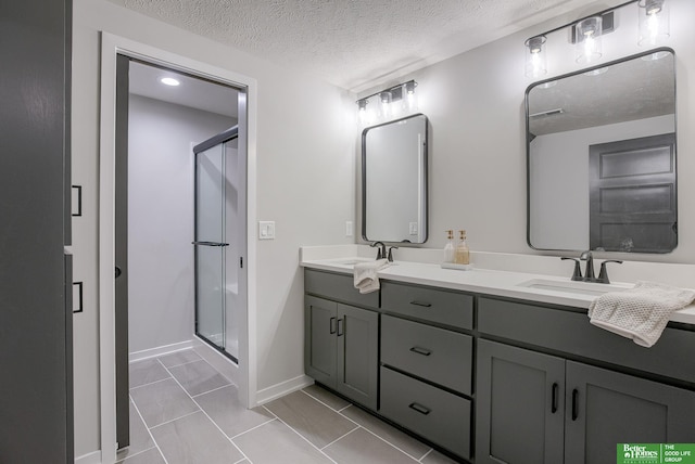 bathroom featuring tile patterned floors, vanity, an enclosed shower, and a textured ceiling