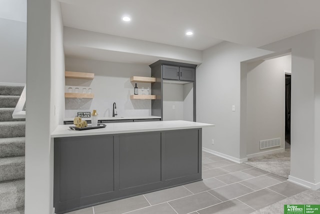 kitchen with range, kitchen peninsula, sink, and light tile patterned floors