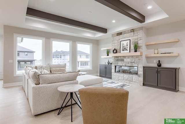 living room featuring a fireplace, beam ceiling, and light hardwood / wood-style flooring