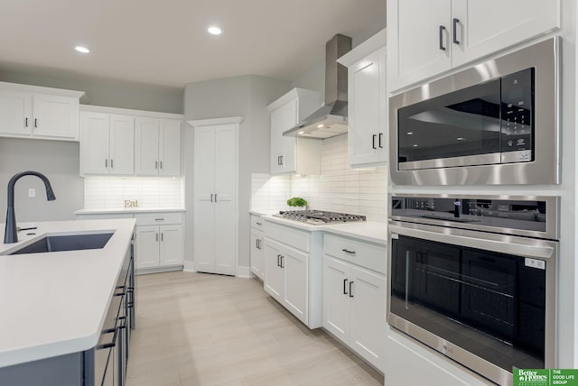 kitchen featuring white cabinetry, appliances with stainless steel finishes, sink, and wall chimney exhaust hood