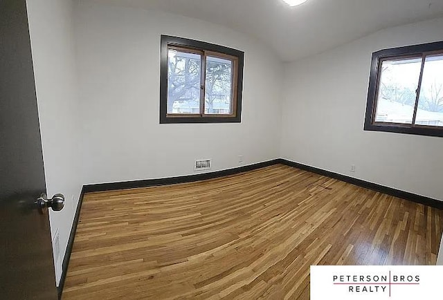 empty room featuring lofted ceiling and wood-type flooring