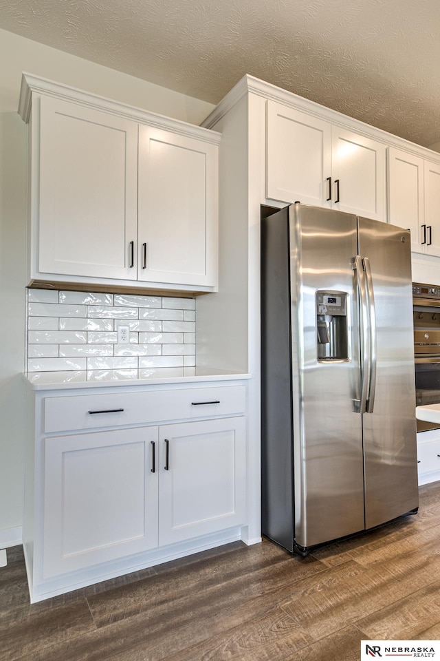 kitchen featuring white cabinetry, dark wood-type flooring, stainless steel fridge, and a textured ceiling