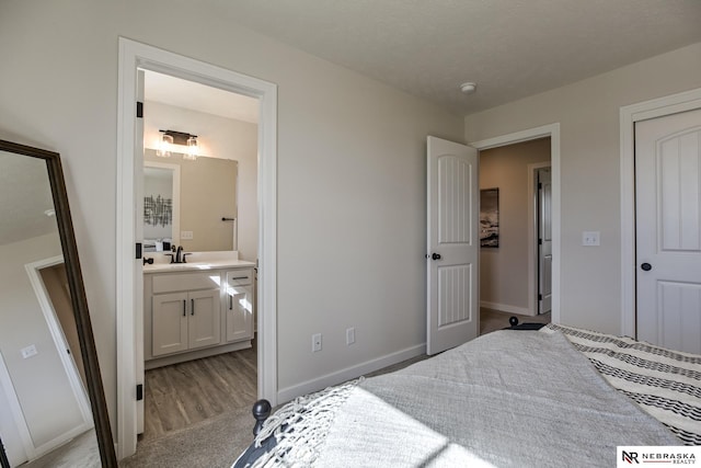 bedroom with connected bathroom, sink, and light colored carpet