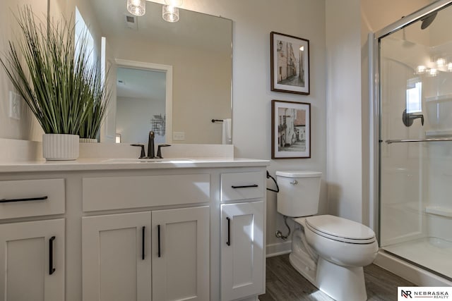 bathroom featuring vanity, toilet, a shower with door, and wood-type flooring