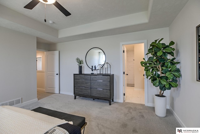 bedroom with light colored carpet, a raised ceiling, and a textured ceiling