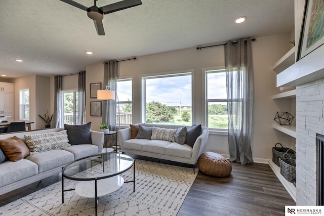 living room featuring ceiling fan, hardwood / wood-style floors, and a textured ceiling