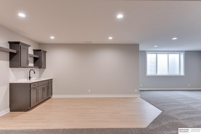 kitchen with light wood-type flooring, sink, and backsplash