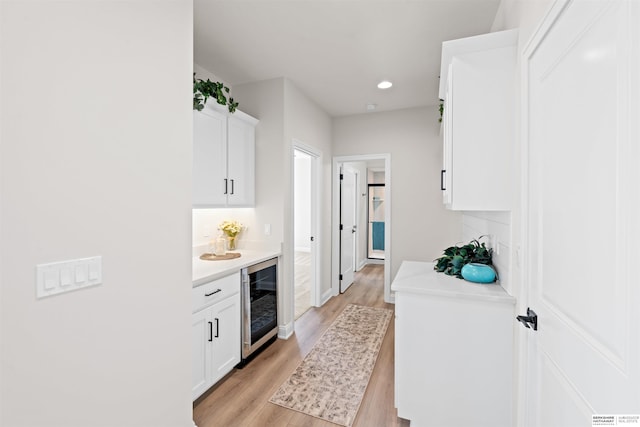 kitchen with light hardwood / wood-style floors, beverage cooler, and white cabinets