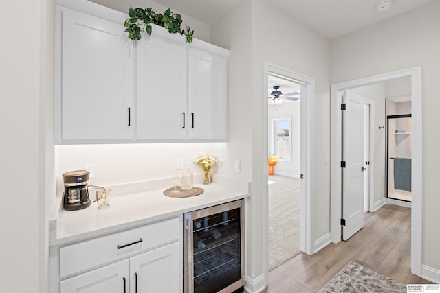 bar with wine cooler, white cabinetry, and light wood-type flooring